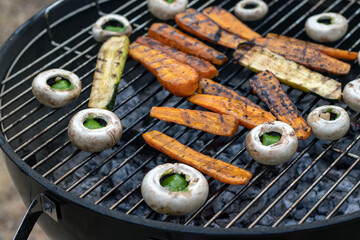 Barbecue végétarien avec des carottes, champignons en galipette au beurre d'escargot cuit sur un grill avec de la braise en été