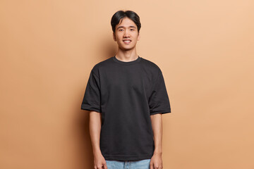 Handsome cheerful Chinese guy with pleasant smile looks directly at camera wears casual black t...