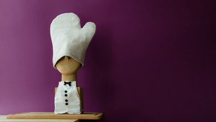 Exclusive composition of the chef's profile. A wooden bust sculpture with a miniature linen apron and a linen kitchen glove instead of a hat. Monochrome background. Sustainability. Minimalism. Cut out