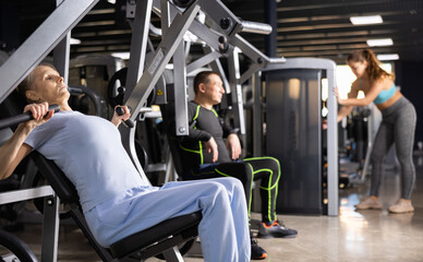 Fototapeta na wymiar Older sportswoman training at chest press machine in gym
