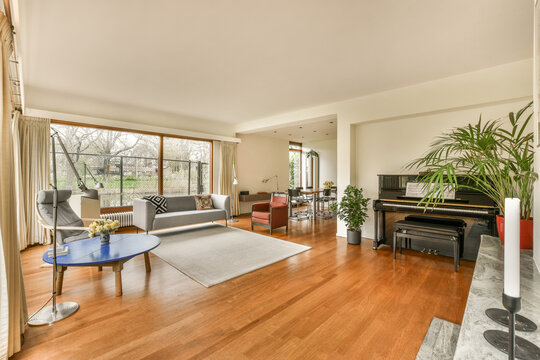 a living room with wood flooring and large windows looking out onto the backyard area in the photo is taken