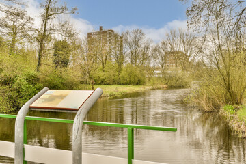 Fototapeta na wymiar an open book on the edge of a body of water with trees and bushes in the background is blue sky