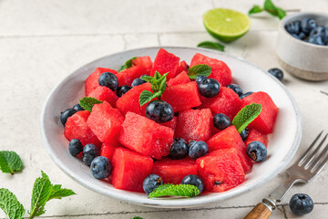 Watermelon salad with blueberries and mint in a plate on white table. Healthy summer vegetarian dessert