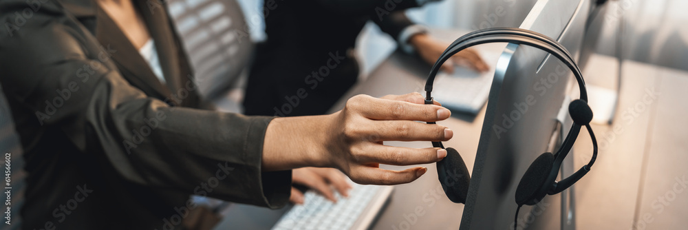 Aufkleber panorama focus hand holding headset on call center workspace desk with blur background of operator t