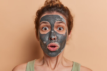 European young woman revels in self care delicately applying soothing clay mask her glowing...