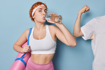 Redhead sporty motivated woman in white cropped top and leggings drinks water feels thirsty after...