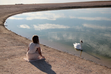 Girl in a dress on the lake with a white swan