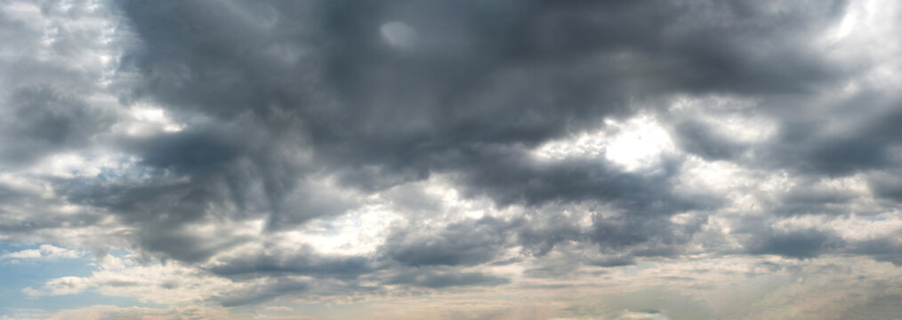 A panoramic view of scattered Dark clouds against a blue sky