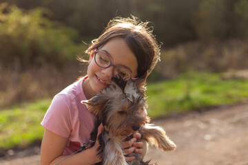 Little girl with a Yorkshire Terrier in the park at sunset.