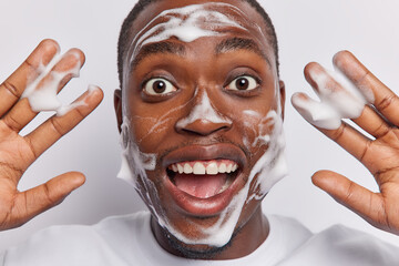 Close up shot of cheerful dark skinned man indulges in rejuvenating moment cleanses and washes his...