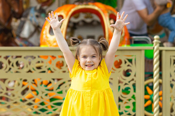 Happy little girl in the amusement park at summer. Happy childhood concept.