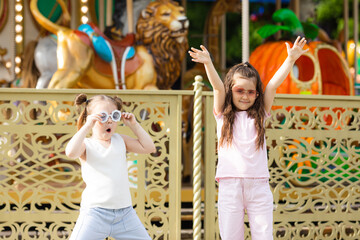 Fototapeta premium Two happy little girls friends have fun in the amusement park at summer. Happy childhood concept.
