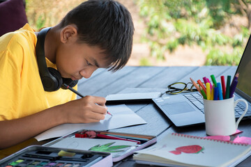 Asian boy in yellow shirt is spending his free time with drawing, sketching, coloring and painting...