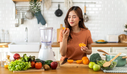 Portrait of beauty body slim healthy asian woman holding orange fruit slice.young girl preparing cook healthy drink with orange juice in kitchen at home,Diet.Self love and Self care