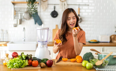 Portrait of beauty body slim healthy asian woman holding orange fruit slice.young girl preparing cook healthy drink with orange juice in kitchen at home,Diet.Self love and Self care