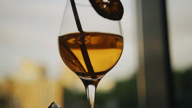 A cool cocktail glass is on the bar in front of the window. Interesting color of the drink. Close-up shooting