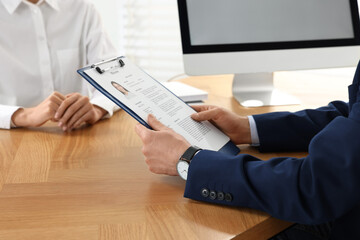 Human resources manager reading applicant's resume in office, closeup