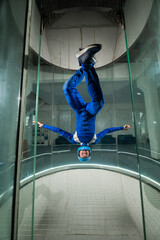 A man in overalls and a protective helmet enjoys flying in a wind tunnel. Free fall simulator