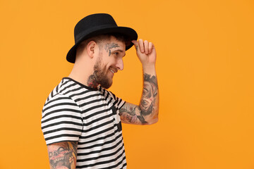 Smiling hipster man wearing stylish hat on orange background. Space for text