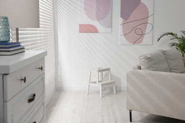 White ladder and abstract pictures on wall in living room