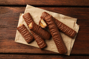 Sweet tasty chocolate bars with caramel on wooden table, top view