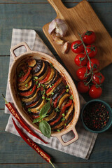Delicious ratatouille and ingredients on wooden table, flat lay
