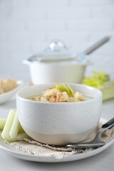 Bowl of delicious celery soup served on white table, closeup