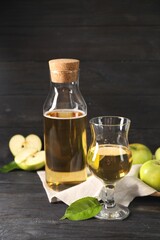 Delicious cider and apples with green leaves on black wooden table