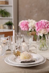 Stylish table setting with beautiful peonies and burning candles indoors