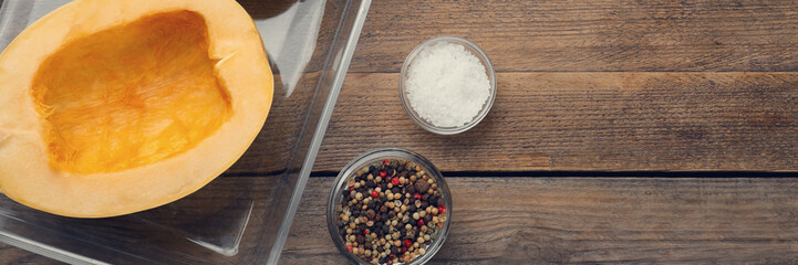 Raw spaghetti squash halves in glass baking dish and spices on wooden table, flat lay. Banner design with space for text