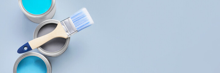Cans with different paints and brush on light background, flat lay. Banner design with space for text