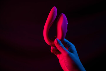 Woman holding a vibrator in neon pink and blue light.