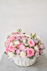 Flower arrangement in Wicker basket. Beautiful bouquet of mixed flowers on a marble table. Floral...