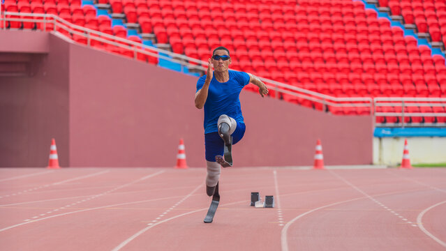 Asian male athlete with prosthetics runs at full speed, demonstrating a powerful practice on stadium track