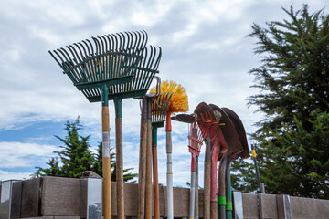 Garden tools, shovel, fork and rake against trees and sky, garden tools concept. Gardeners truck...