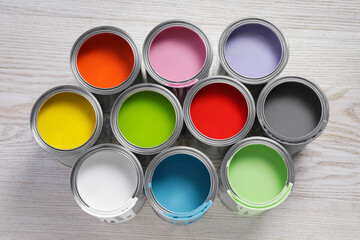 Cans of different paints on white wooden table, flat lay
