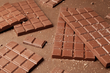 Pieces of tasty chocolate on brown background
