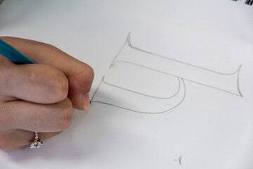 A person drawing a letter with a pencil 