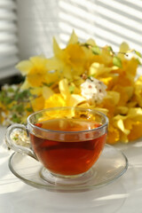 Cup of aromatic tea and beautiful yellow daffodils on windowsill. Space for text