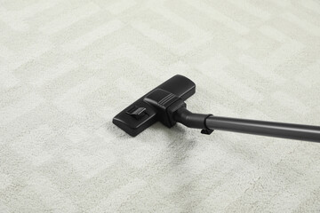 Hoovering white carpet with modern vacuum cleaner