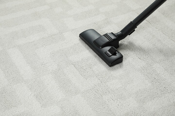 Hoovering white carpet with modern vacuum cleaner. Space for text