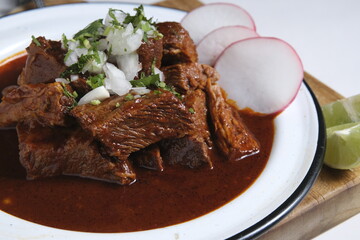 A plate of beef birria tacos with a red sauce and radishes