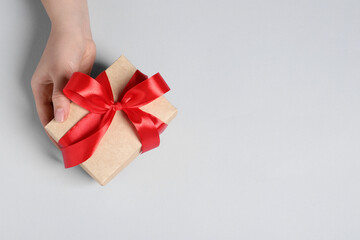 Woman holding gift box with red bow on white background, above view. Space for text