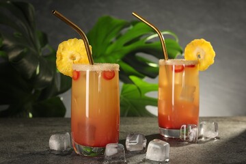 Glasses of tasty pineapple cocktail and ice cubes on grey table. Space for text
