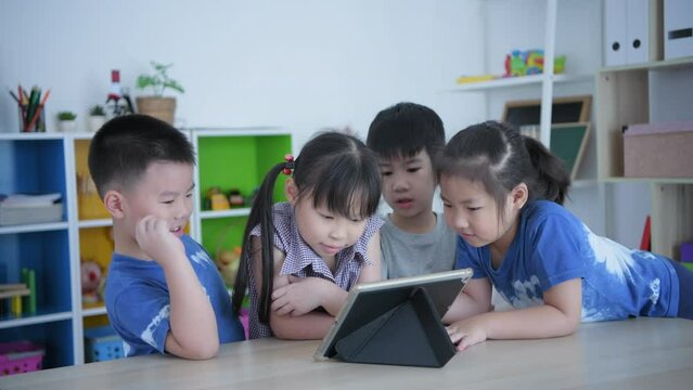 Educational concept of 4k Resolution. kindergarten teacher teaching children using tablet in classroom.