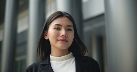 Charming Young Asian businesswoman in suit at front of modern office