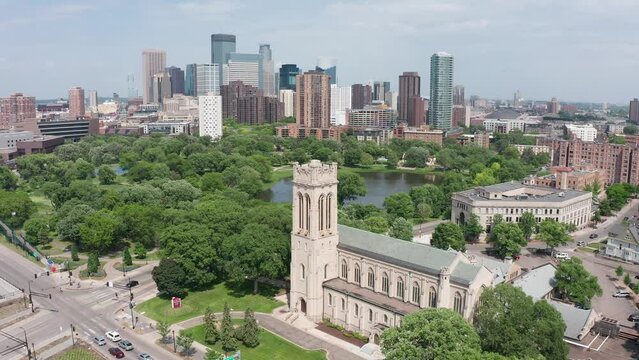 Wide reverse aerial pullback shot of Saint Mark's Episcopal Cathedral with the Minneapolis skyline in the background. 4K