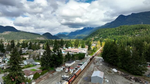 Long Freight Train Traveling Through Industrial Area Near The Town In Hope, BC, Canada. - aerial