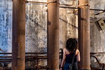 Fototapeta na wymiar Back view of a woman exploring an old abandoned factory.