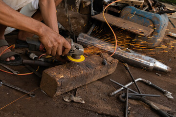 A welder cutting metal with a grinder prepares to weld